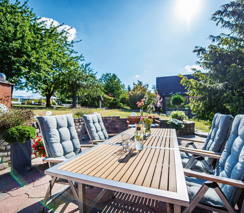 Gartentisch mit Stühlen unter sonnigem Himmel, Terrasse mit Möbeln bei Sonnenschein, Grünbelag Entferner, Mellerud