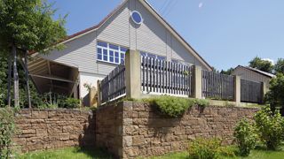 Haus mit Gartenzaun, Steinmauer, braun steine, Santuro